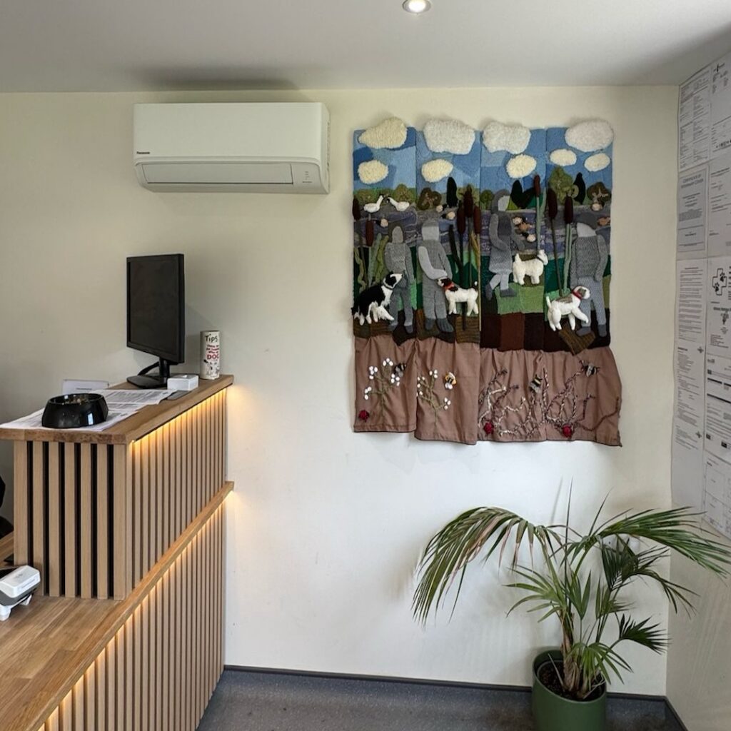 Reception room at the Kennels, Handmade dog tapestry on the wall with the air conditioning unit above.